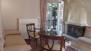 Una habitación acogedora con una mesa y sillas de madera, un sofá, una chimenea y una ventana con cortinas.