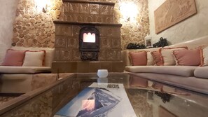 A cozy living room with a stone wall, a fireplace, and a sofa with decorative pillows.