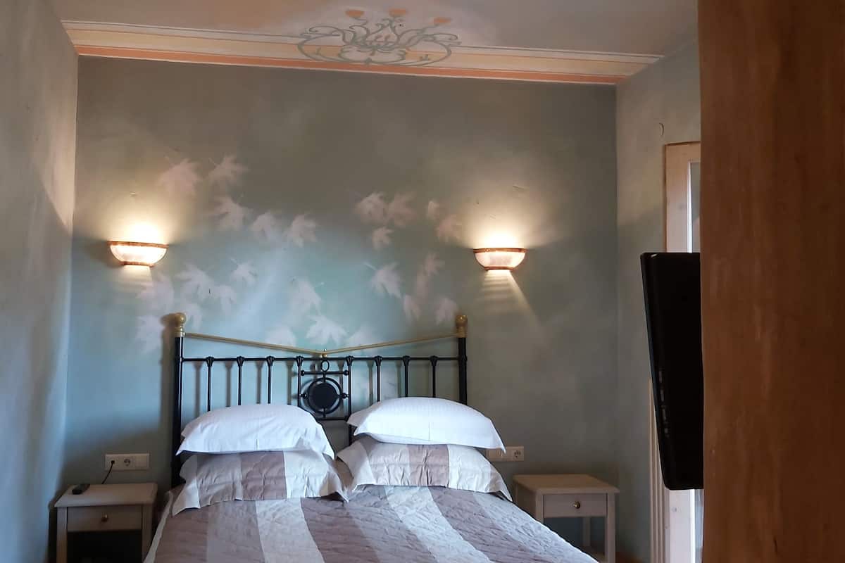 A bedroom with a bed, two bedside tables, and wall-mounted lamps.