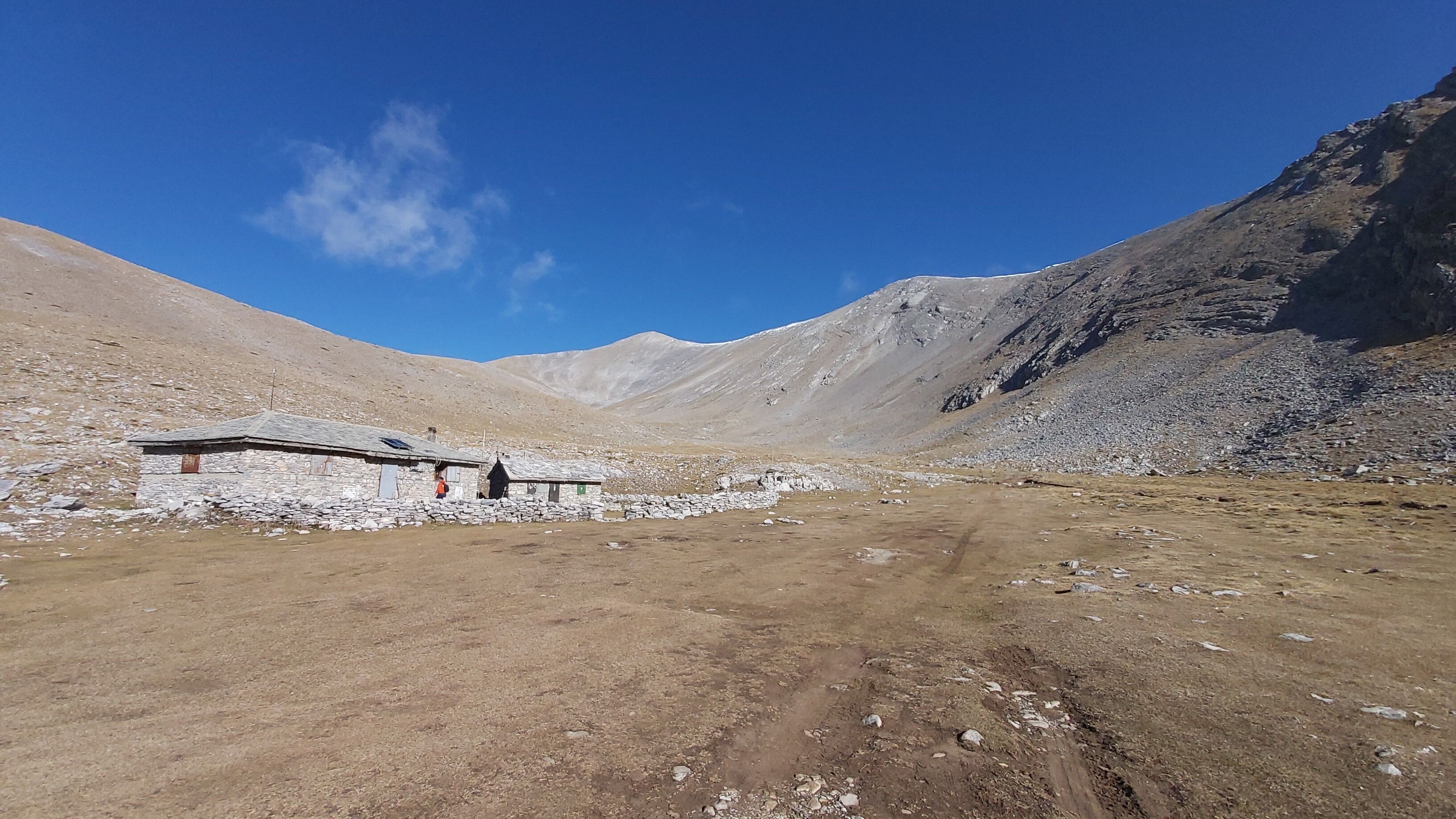 A remote, rocky landscape with a dirt path leading to a small stone structure.