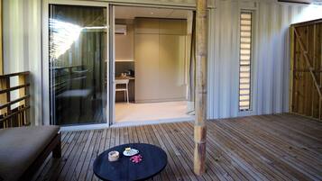 Une terrasse en bois avec une table ronde, une chaise et une petite table sur laquelle sont posés divers objets.