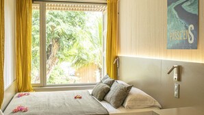 Een slaapkamer met een bed, gordijnen, een raam, een wandlamp en een schilderij.