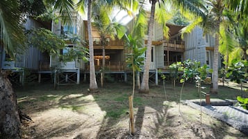 A tropical resort with multiple wooden structures, palm trees, and a dirt path.