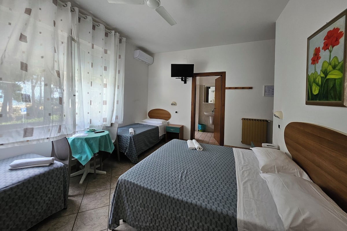 A hotel room with two single beds, a desk with a chair, a television, and a painting on the wall.