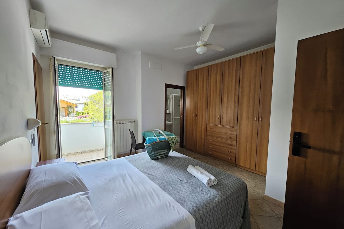 A bedroom with a bed, a suitcase, a ceiling fan, and a wardrobe.