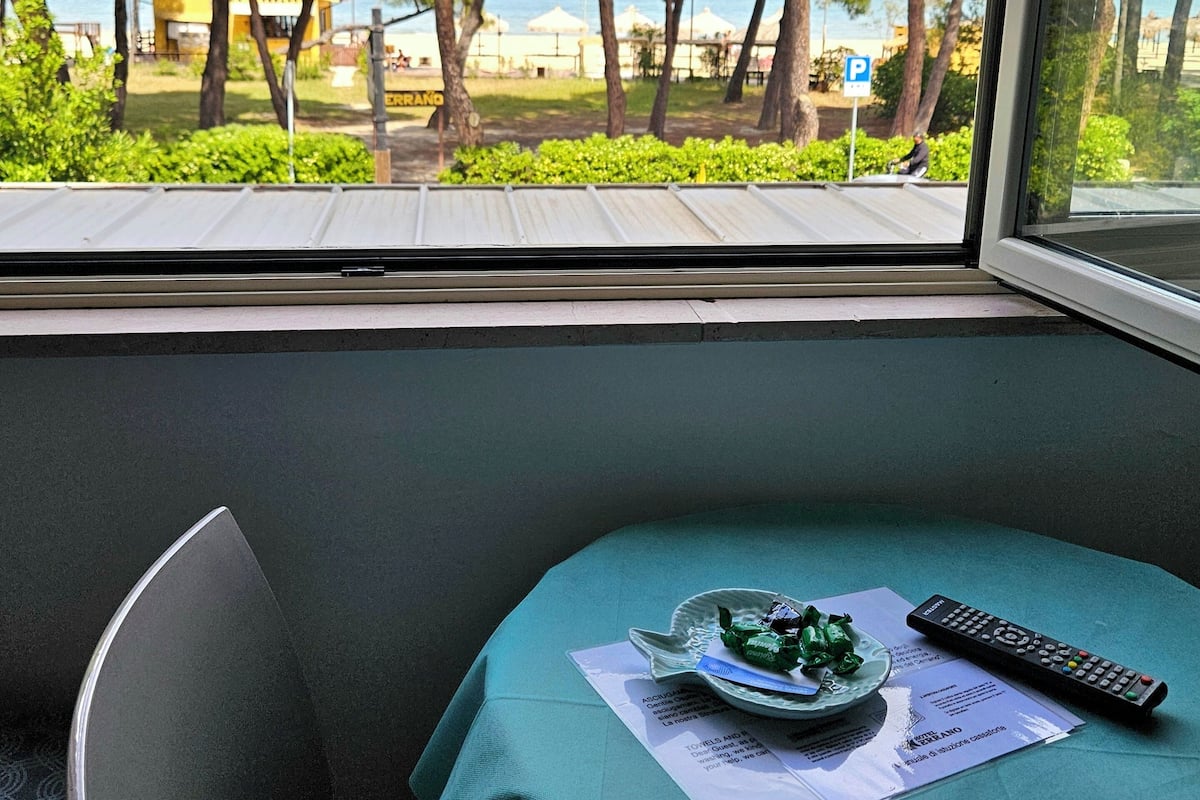 A room with a view of the sea, a table with a remote control, and a menu on the table.
