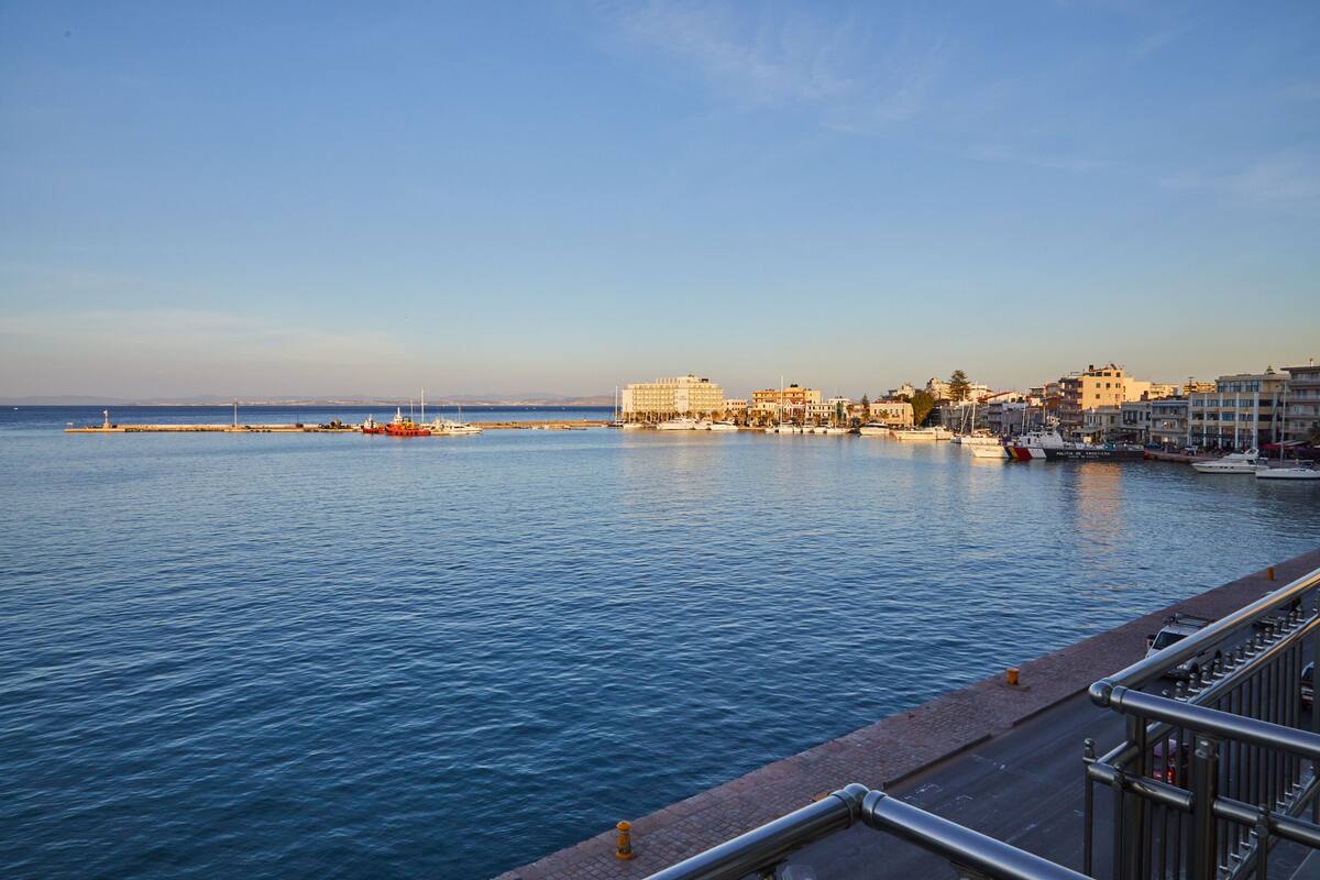 A waterfront cityscape with buildings along the shore and a calm sea.