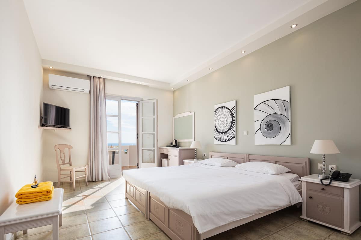 A modern bedroom with a large bed, bedside tables, a TV, and artwork on the walls.