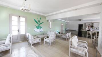 A spacious living area with multiple seating options, a kitchen in the background, and a dining area.
