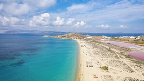 A coastal landscape with a beach, clear blue waters, and a mountainous backdrop. - Kavuras Village Hotel & Suites (Naxos)