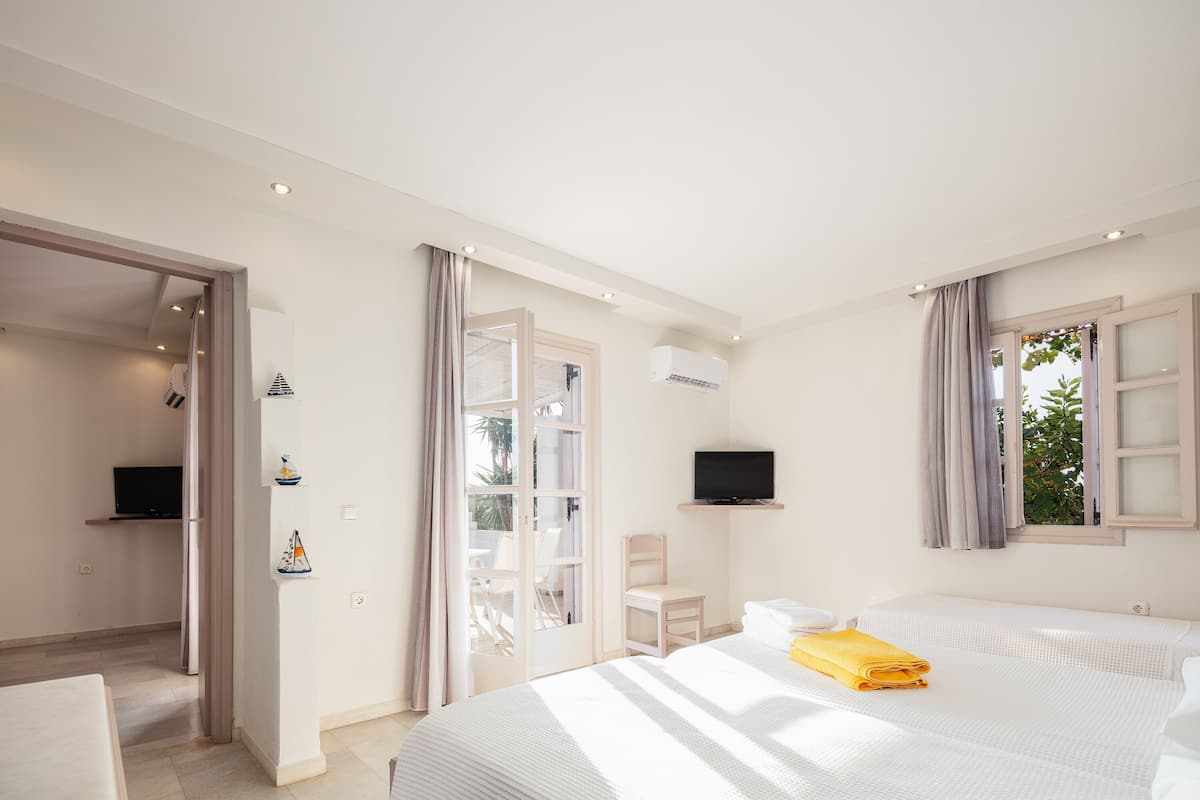 A hotel room with two beds, a TV, a desk, and a chair.