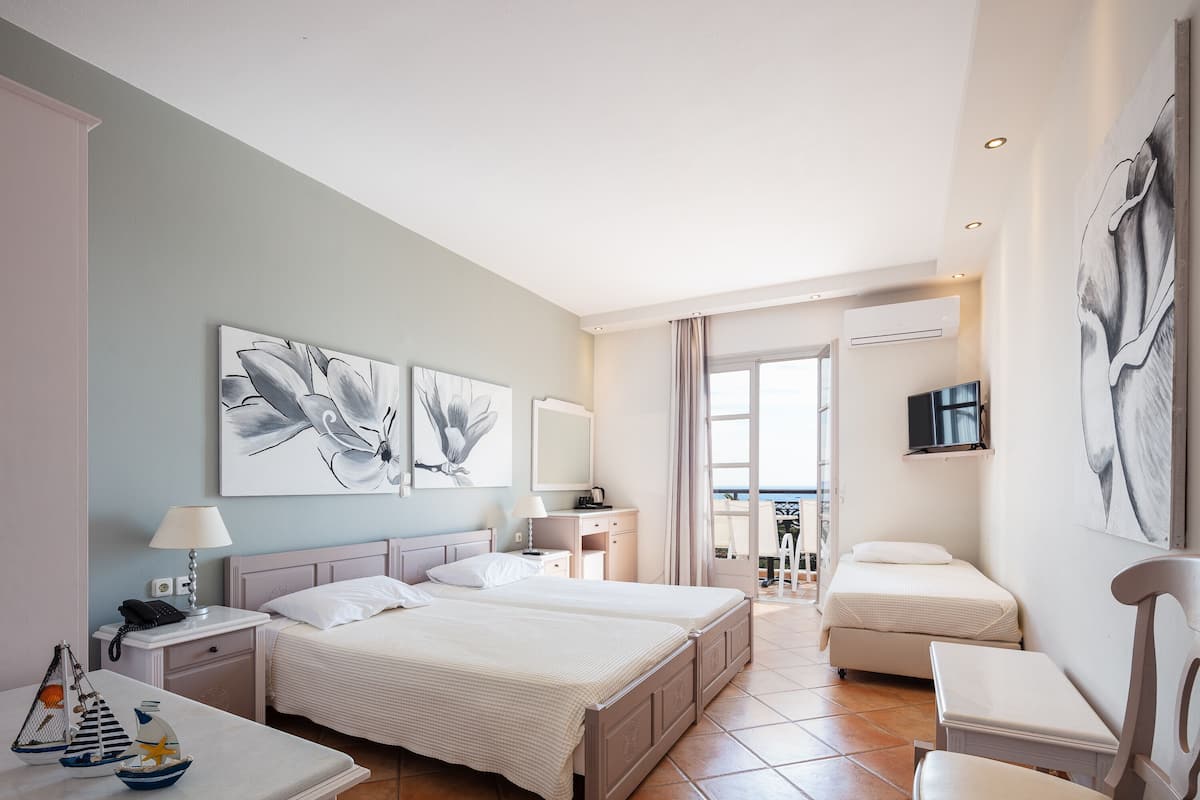 A hotel room with two beds, a desk, a chair, and artwork on the walls.