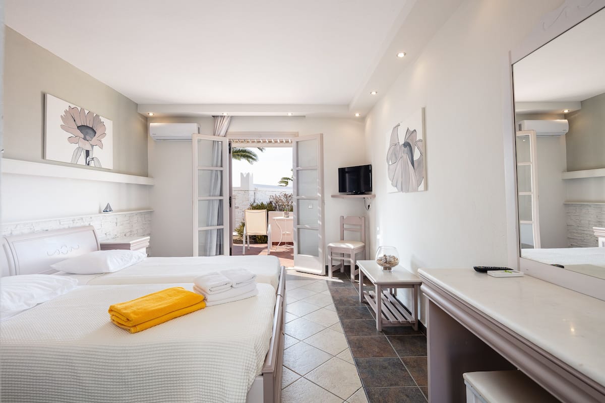 A hotel room with a bed, a desk, a chair, a TV, and a bathroom with a shower.