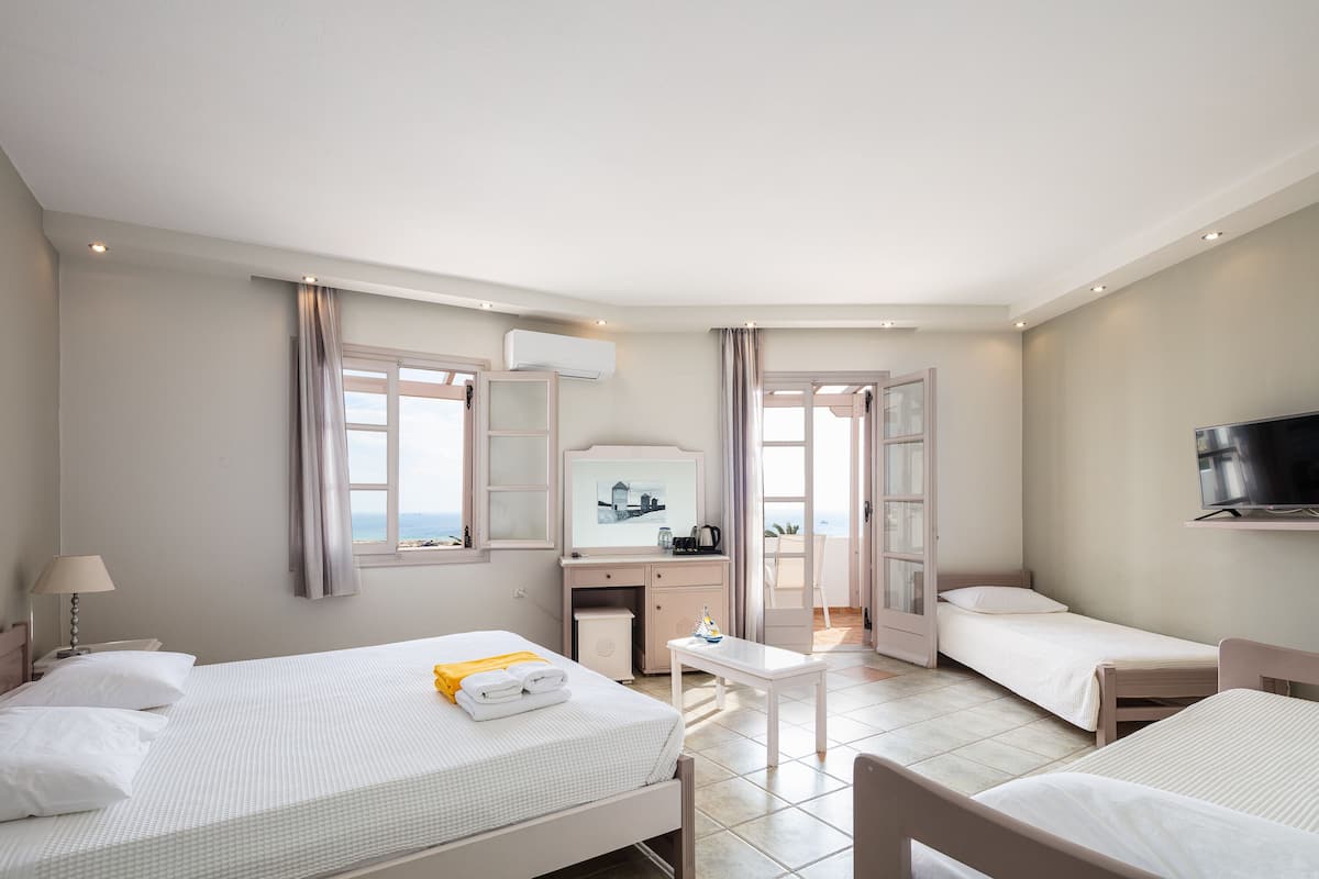 A hotel room with two beds, a desk, a TV, and a window with curtains.