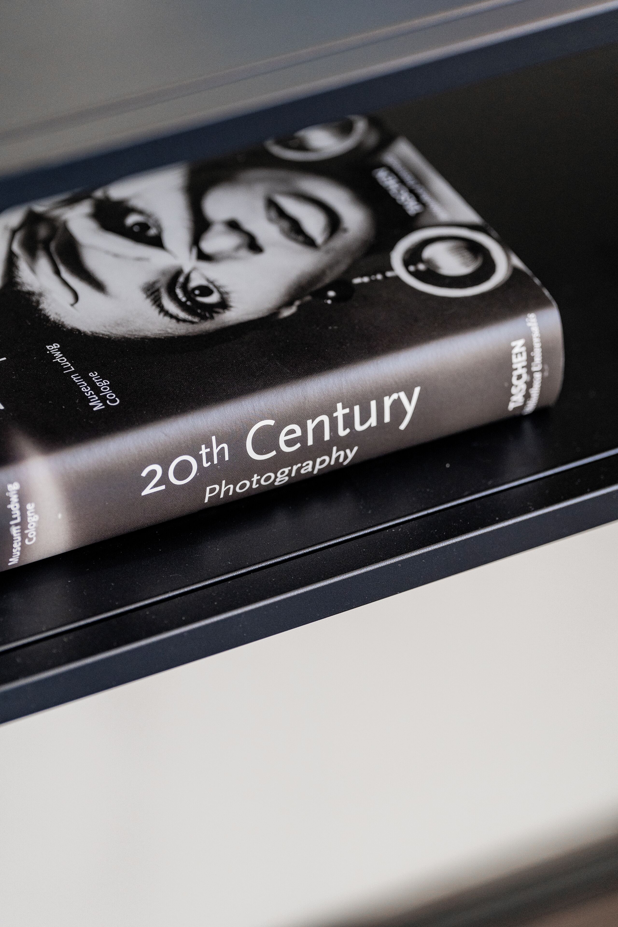 Um livro intitulado 'Fotografia do Século XX' numa estante.