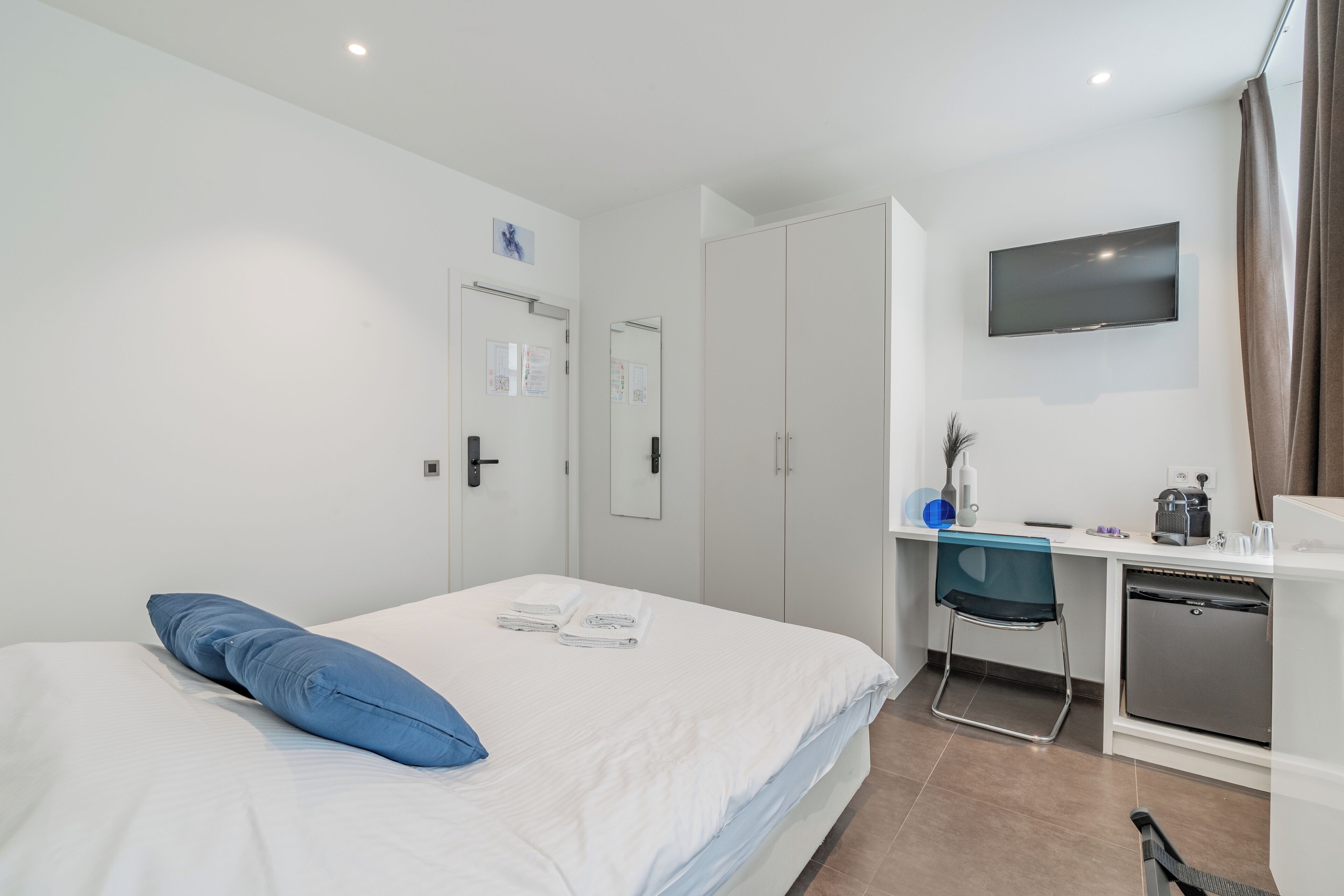 Una habitación de hotel moderna con cama, escritorio, televisión y kitchenette.