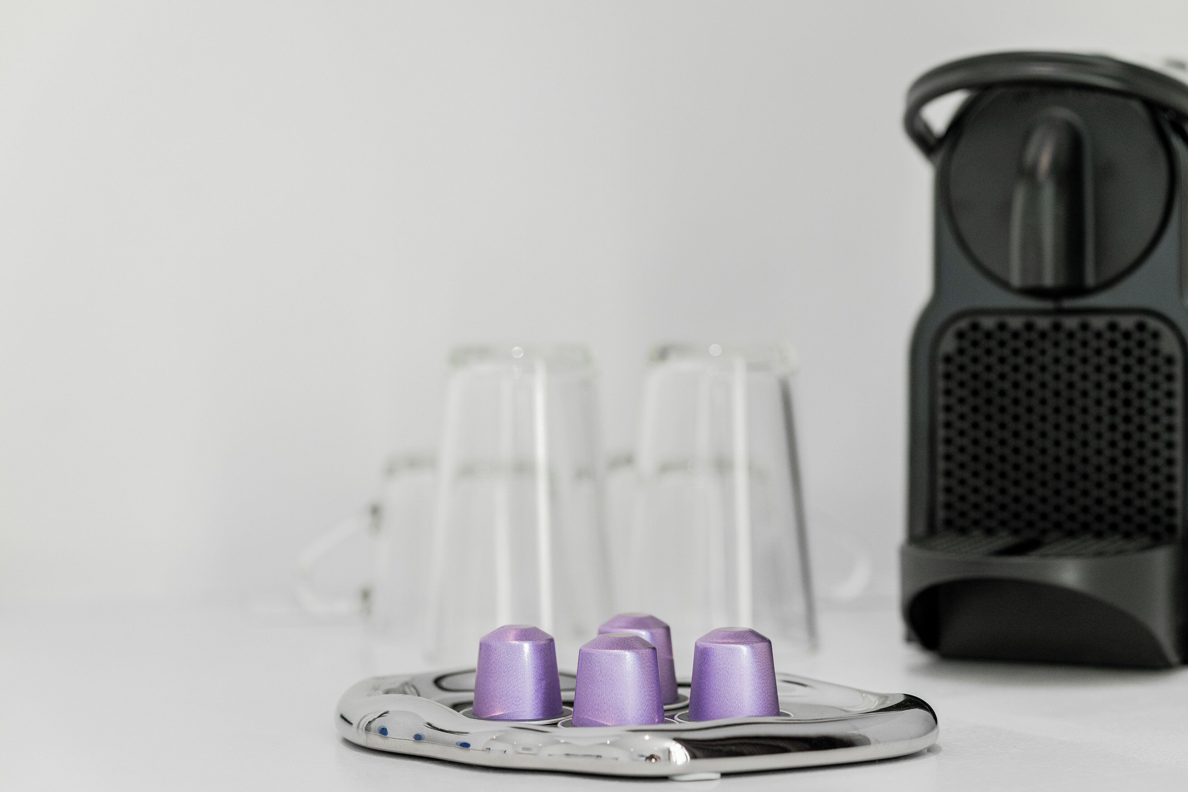 A white table with a white speaker and a white device with purple buttons.