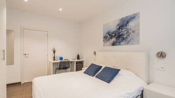 A modern bedroom with a large bed, a desk, and a chair.