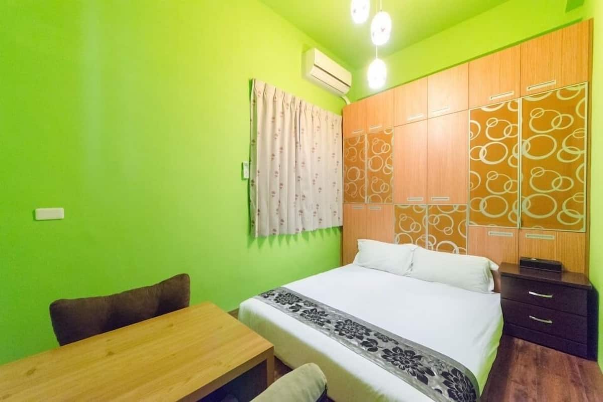 A room with a bed, a wooden table, a chair, and a wardrobe with circular patterns.