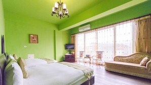 Ein Zimmer mit einem großen Bett, einem Schlafsofa, einem Fernseher und einem Fenster mit Vorhängen.