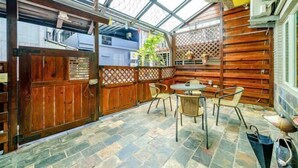 Ein überdachter Patio-Bereich mit Holzlattenzaun, Steinboden und einem Tisch mit Stühlen.