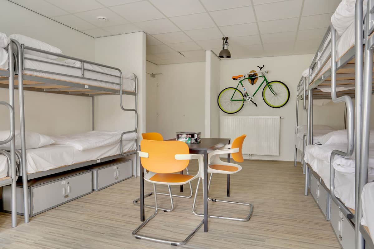 Un dormitorio con literas, una mesa con sillas y una bicicleta colgada en la pared.