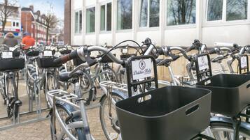 A row of bicycles parked in front of a building with windows and a sign that reads "Duchies Hotel."