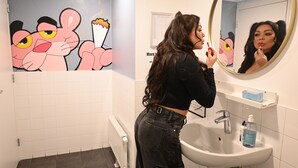 Une salle de bain avec un lavabo blanc, un miroir et des personnages de dessins animés sur le mur.