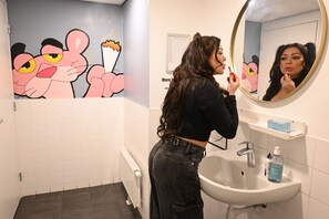 Ein Badezimmer mit einem weißen Waschbecken, einem Spiegel und Zeichentrickfiguren an der Wand.