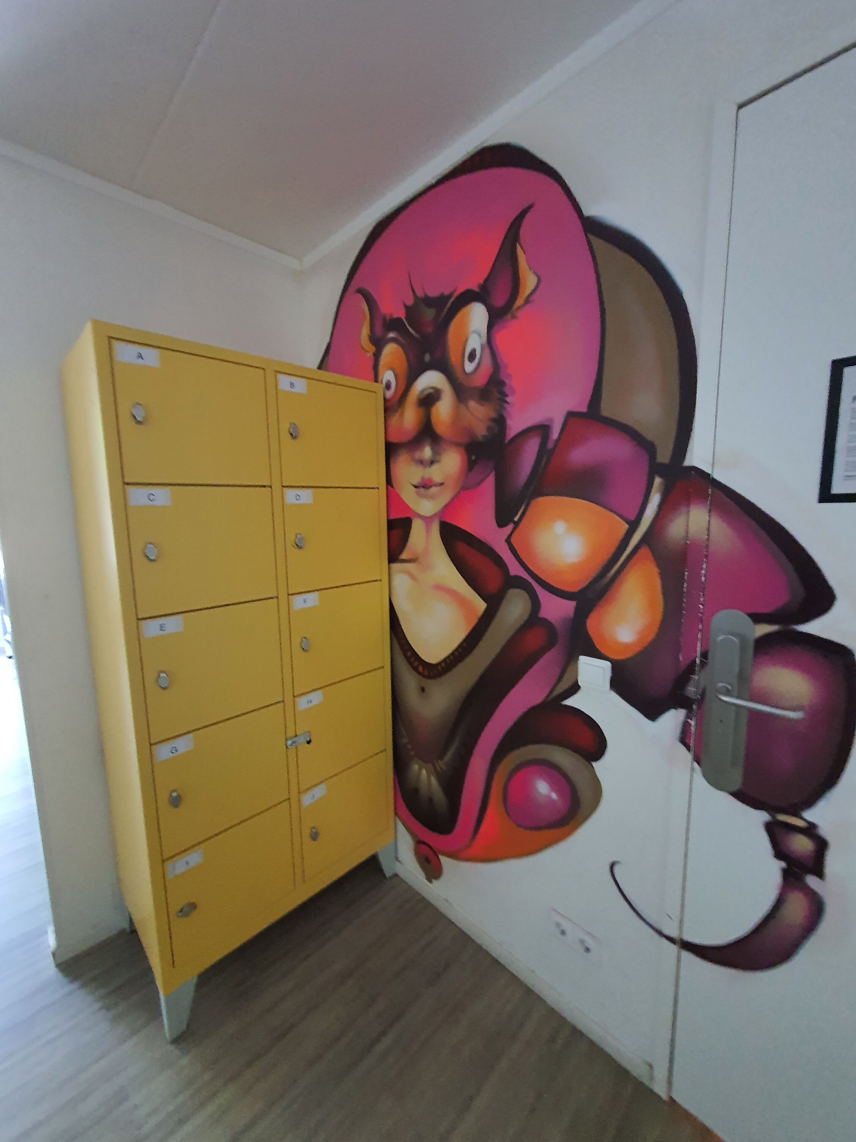 Ein Zimmer mit einem gelben Aktenschrank und einer Wandmalerei einer Comicfigur.