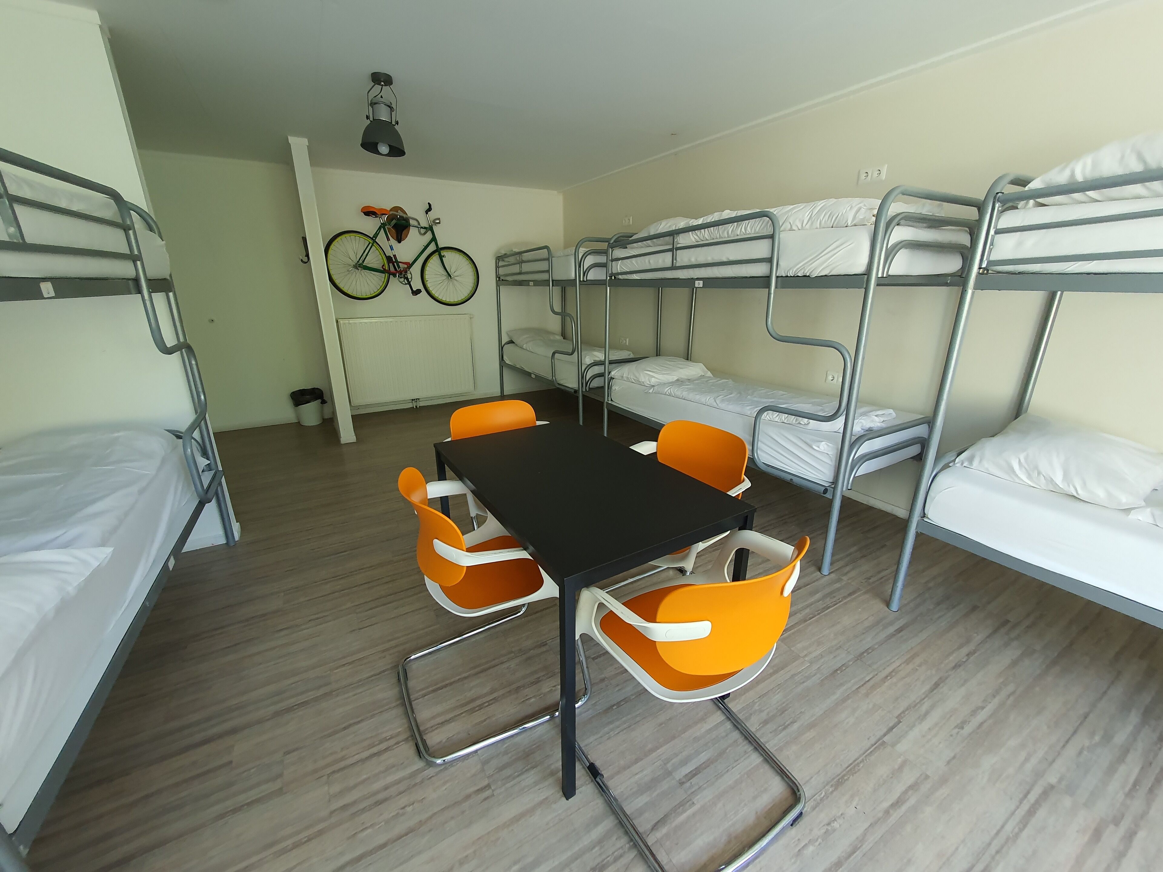 Une chambre de dortoir avec des lits superposés, une table et des chaises orange.
