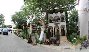 A guest house with a stone facade, arched windows, and a balcony with flags.
