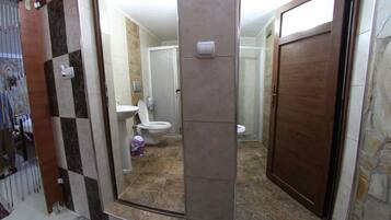 Eenvoudige kamer | Badkamer | Een douche, een haardroger, handdoeken, zeep