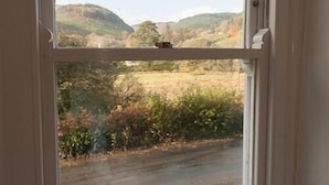 A window with a view of a rural landscape, including hills and vegetation. - Bronfelin & Troed-y-rhiw Holiday Cottages (Llanwrtyd Wells)