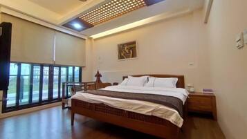 Un dormitorio con una cama grande, ventilador de techo, ventana con vistas y un cuadro en la pared.