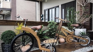 Una bicicleta de madera con asiento y manillar, estacionada sobre una terraza de madera.