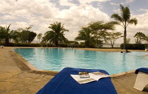 A poolside area with lounge chairs, a pool, and palm trees. - Jacaranda Lake Elementaita Lodge (Gilgil)