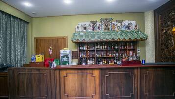 A bar area with wooden cabinets, shelves of liquor bottles, and a decorative ceiling.