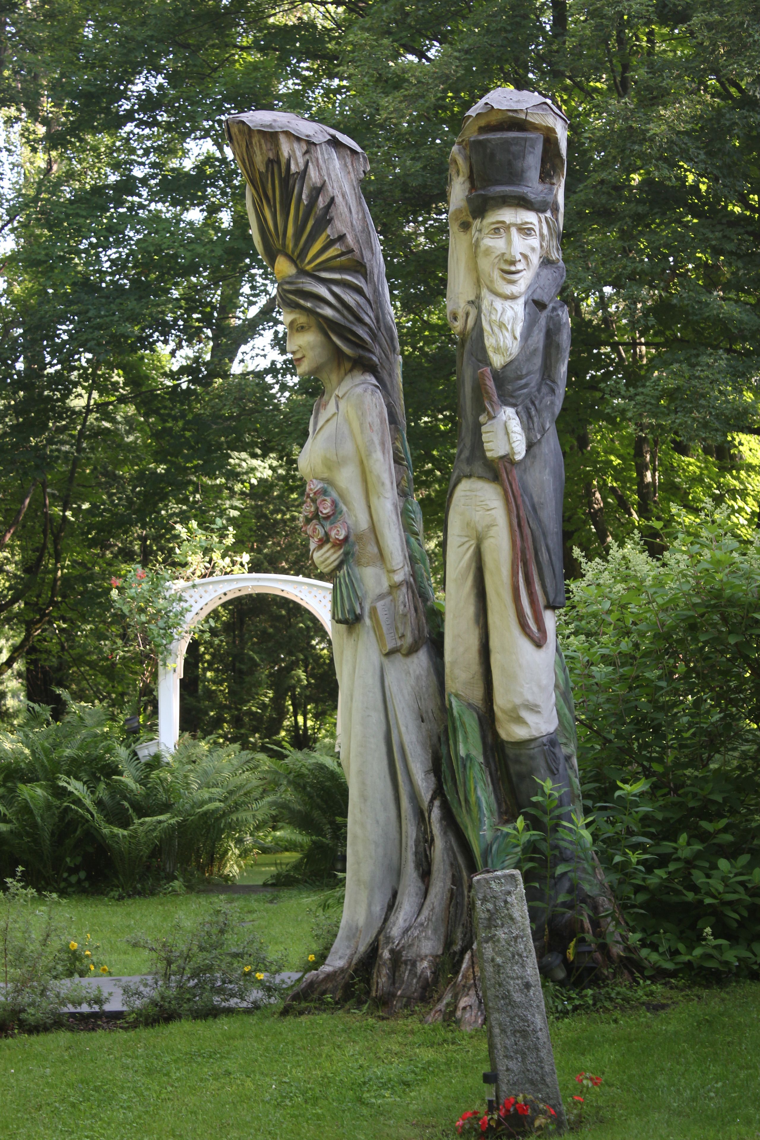 A garden statue of a man and woman, with a white archway in the background.
