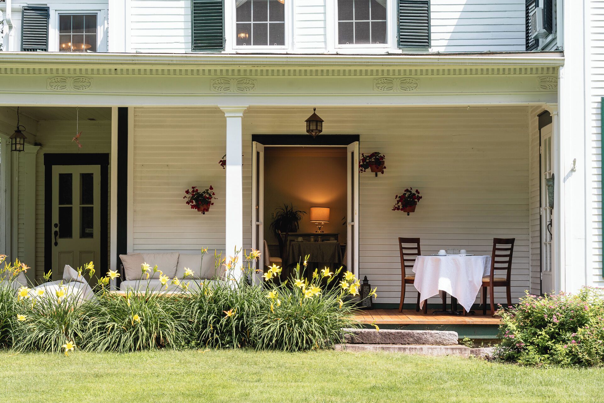 A porch with a table and chairs, a door, and potted plants.