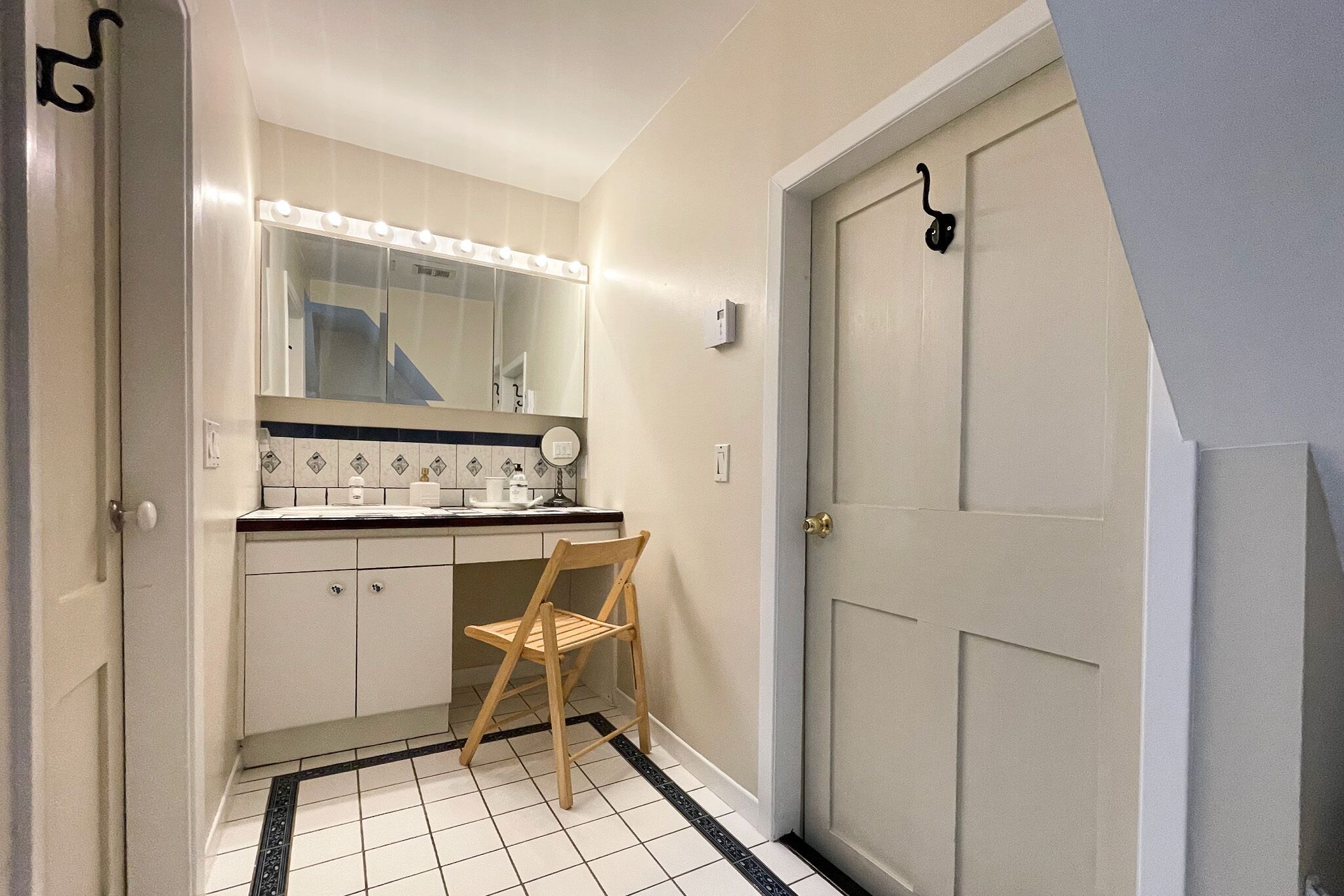 Une petite salle de bain avec un miroir, un meuble-lavabo et une chaise.