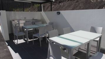 Un patio con mesa y sillas, una pequeña cocina con fregadero y una pared de piedra.