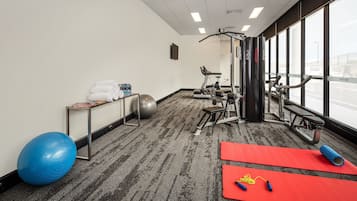 A gym with exercise equipment, a large exercise ball, and red mats.