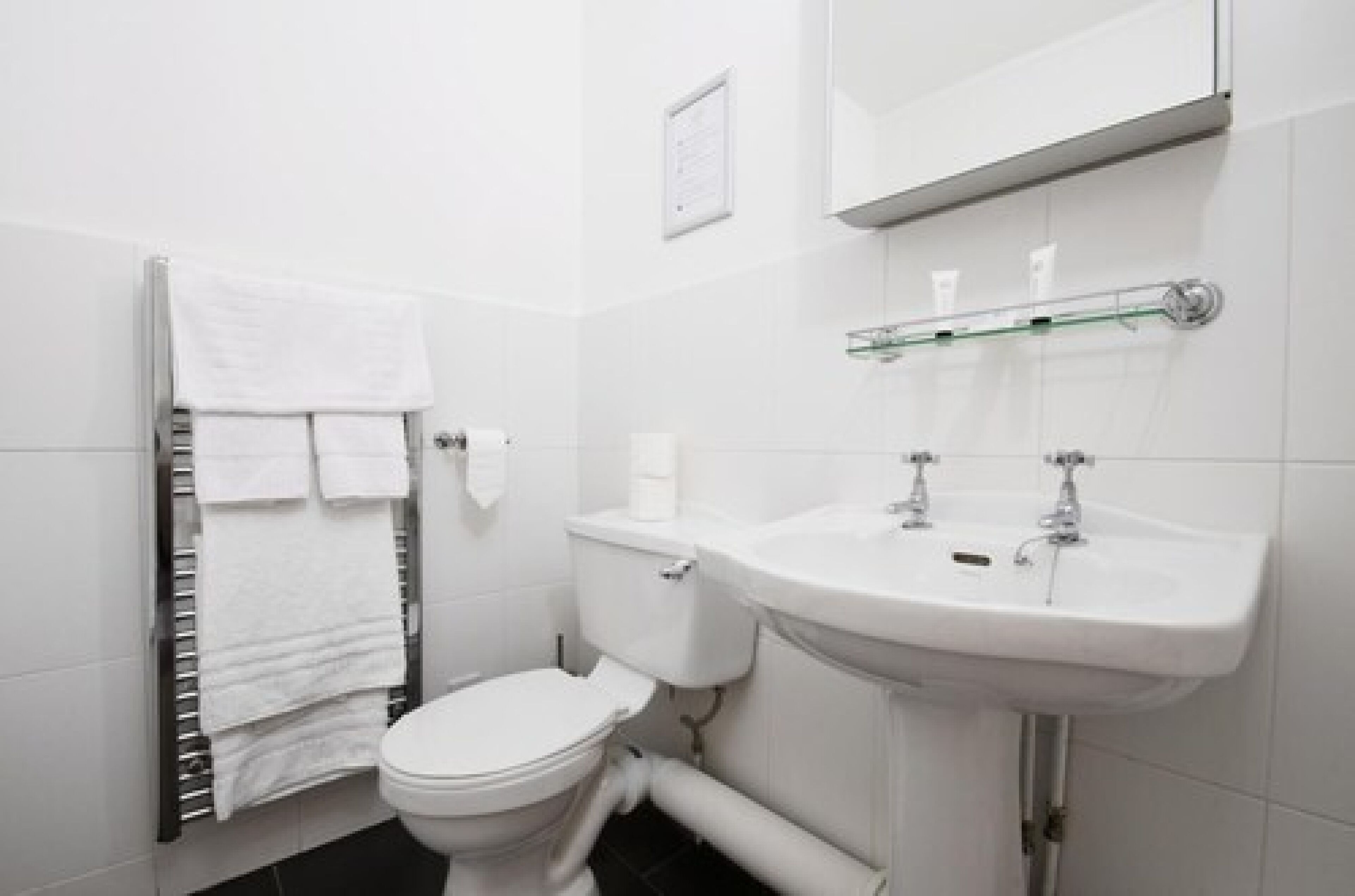 A modern bathroom with a toilet, sink, and towel rack.