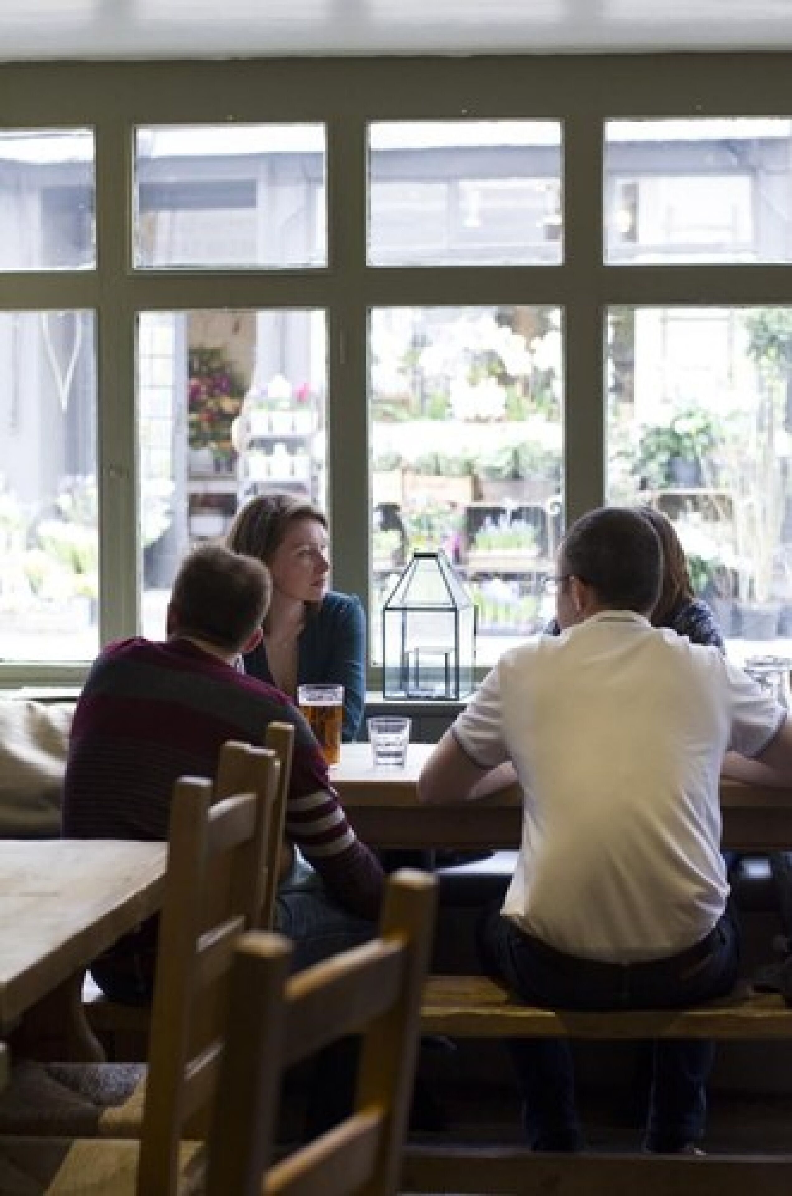 Un groupe de personnes est assis autour d’une table à l’intérieur d’un bâtiment doté de grandes fenêtres.