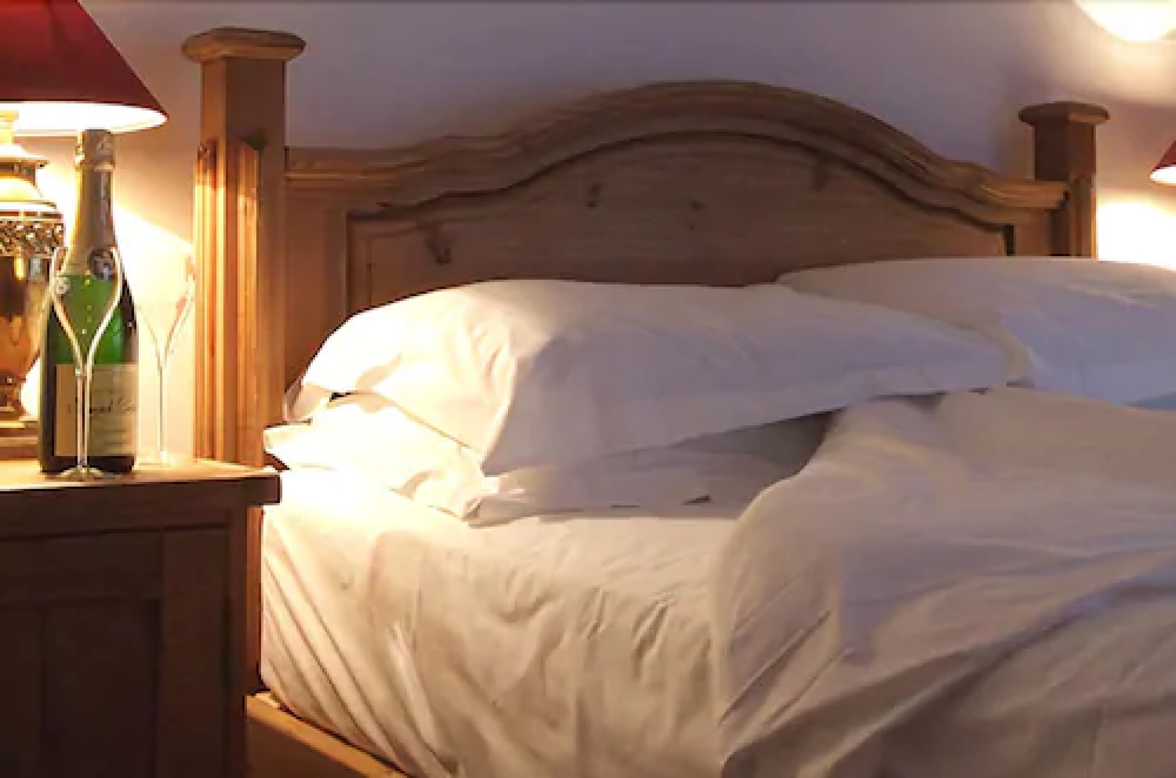 A bed with white linens and a wooden headboard.