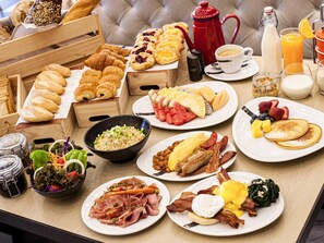 A breakfast buffet with various pastries, fruits, and a coffee station.