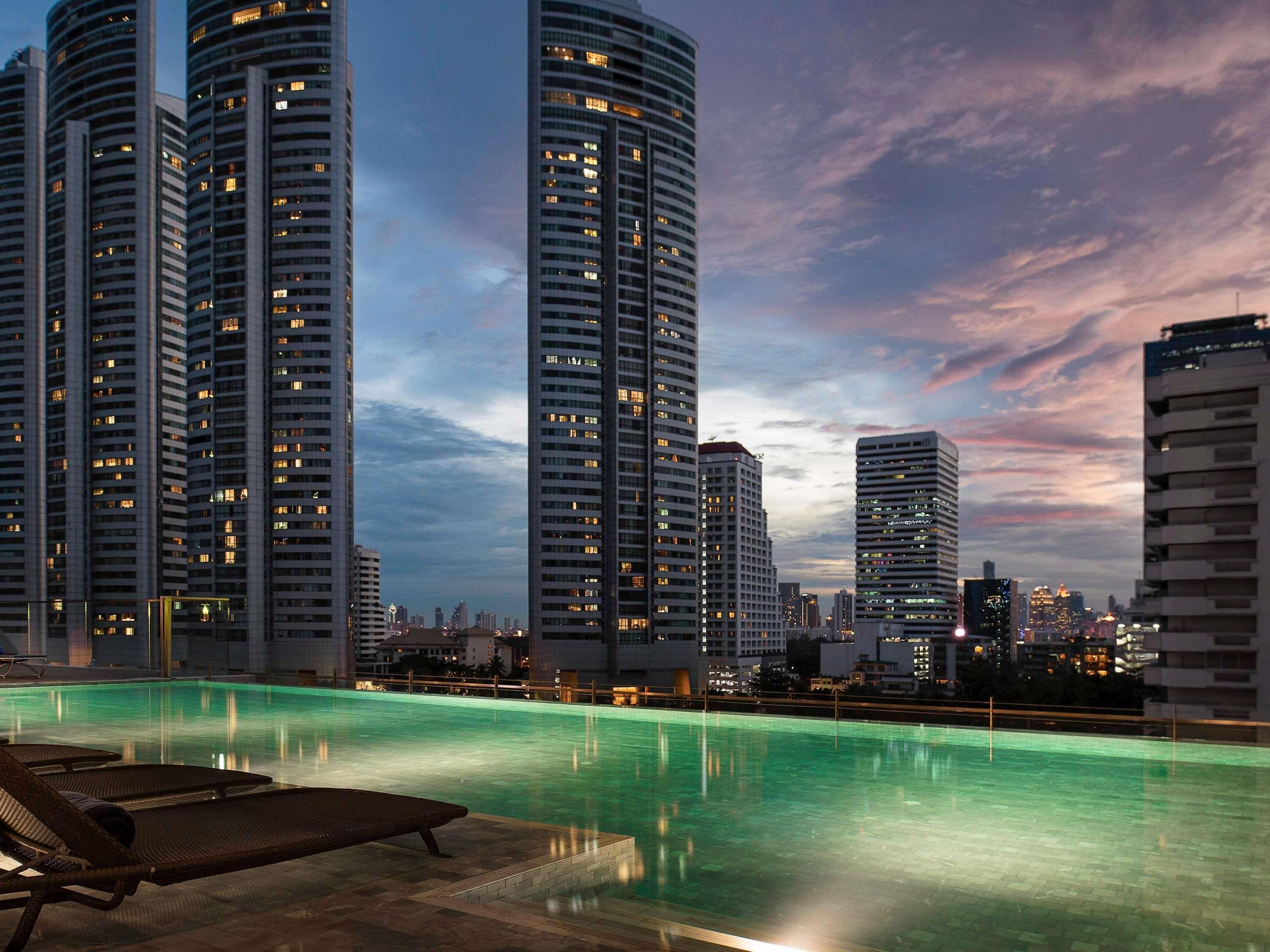 Una piscina al aire libre, sombrillas, sillones reclinables de piscina