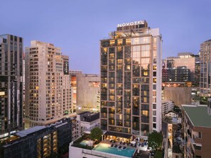 A high-rise hotel with a rooftop pool, surrounded by other buildings.