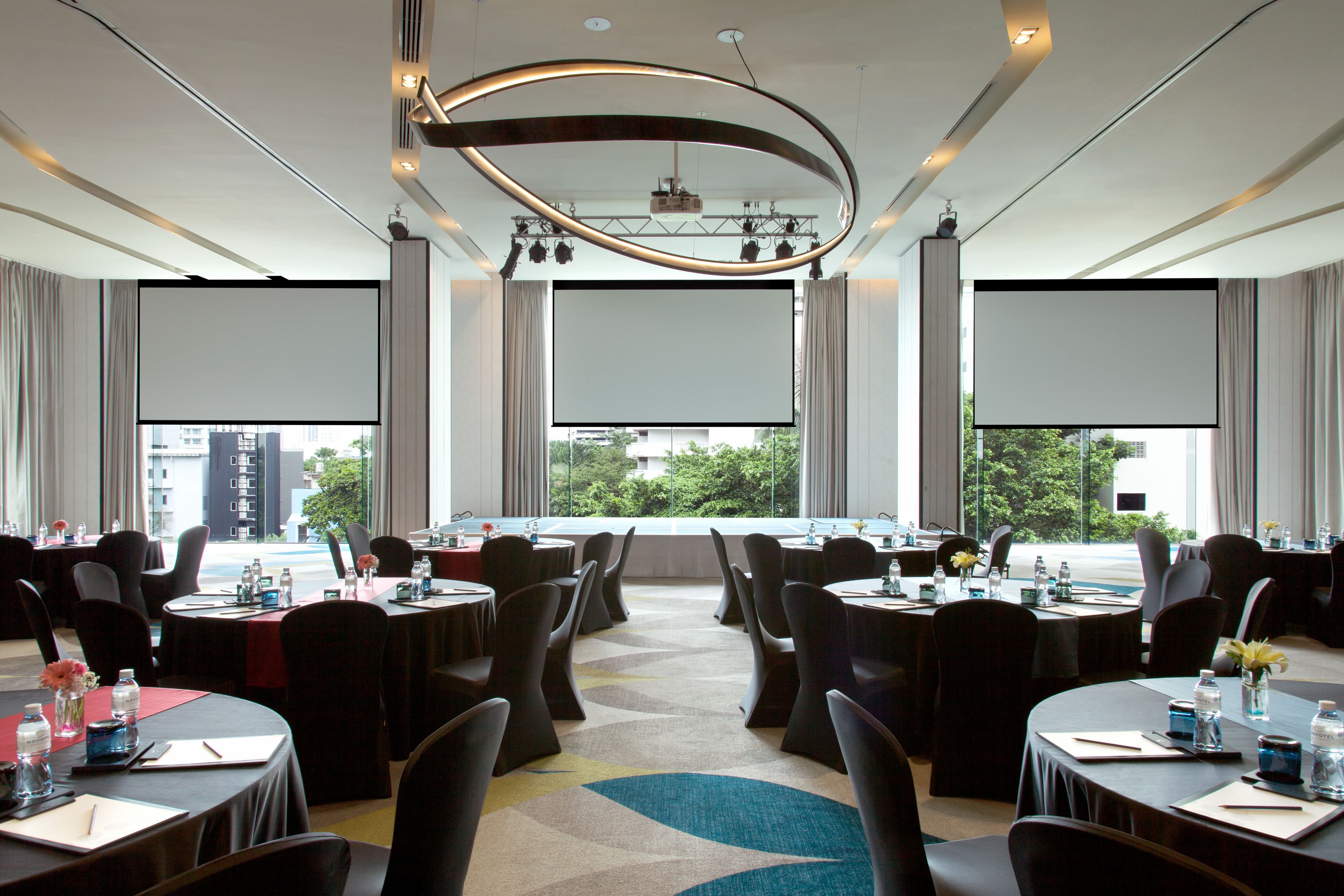 Una sala de conferències amb diverses taules, cadires i una gran pantalla al capdavant.
